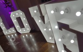 giant white light up love letters at a wedding reception with purple uplights